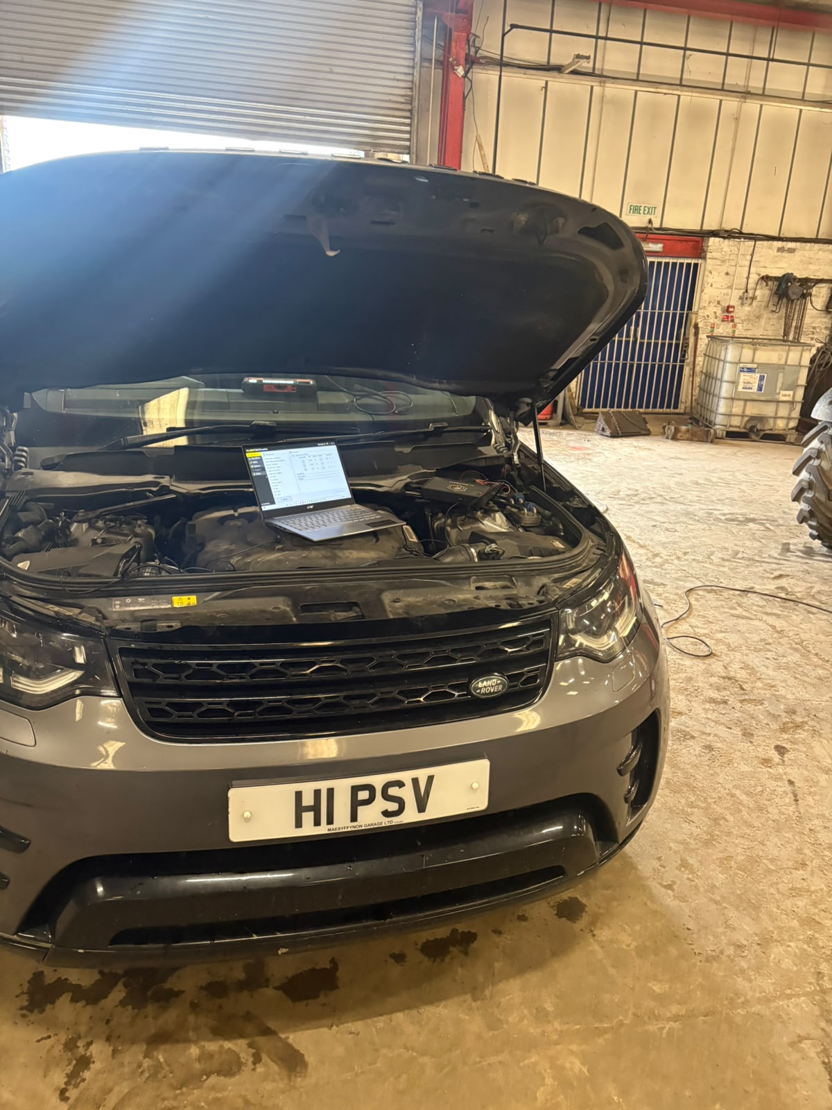 Diagnostic laptop running live ECU fault-code analysis on a Land Rover Discovery in the workshop